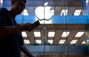 Apple alerta novas vítimas para ataques de spyware em todo o mundo A pedestrian uses a smartphone while walking past an Apple store and logo in Hong Kong.