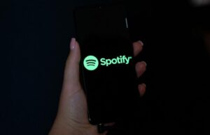 O serviço premium do Spotify adiciona 5 milhões de usuários e a empresa registra um lucro operacional recorde Hand holding a mobile phone with the logo of Spotify on its screen.