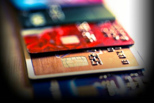 Close up macro color image depicting an abstract view of a collection of debit and credit cards and numeric digits.