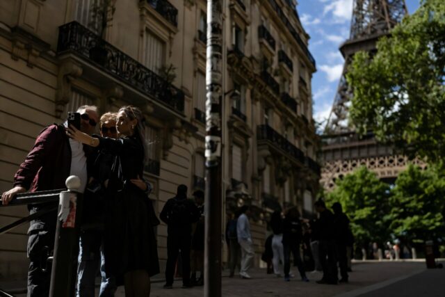 Três pedestres tiram uma selfie no beco pitoresco no final da Rue de L'Höxesite, Paris