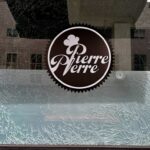 Um buraco de bala e uma janela fraturada são visíveis no restaurante Pierre Pierre, no térreo da Tribune Tower, na 409 13th Street, no centro de Oakland, enquanto um homem está dentro do negócio, 3 de maio de 2025. (Ray Chavez/Bay Area News Group)
