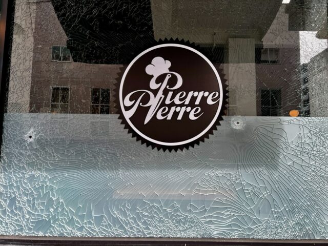 Um buraco de bala e uma janela fraturada são visíveis no restaurante Pierre Pierre, no térreo da Tribune Tower, na 409 13th Street, no centro de Oakland, enquanto um homem está dentro do negócio, 3 de maio de 2025. (Ray Chavez/Bay Area News Group)