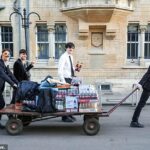 Estudantes da Universidade de Oxford com olhos foram vistos como chegaram em casa do baile de maio no início da manhã após a dança a noite toda após a noite da noite. Um grupo que incluía um homem que segurava uma cobertura de creme empurrou a vagão que transporta caixas de cerveja, alguns sapatos e vários outros objetos na estrada