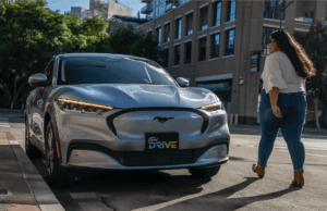 Ford aumenta os preços do Mustang Mach-E devido às tarifas de Trump Woman walks up to silver Mustang Mach-E. License plate says "Ford Drive"