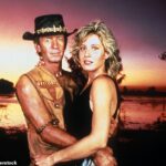 Uma fonte compartilhou exclusivamente uma atualização sobre a atriz aposentada Linda Kozlowski (à direita), conhecida por seu papel no Crocodile Dundee, em 1986, ao lado de Paul Hogan (à esquerda)