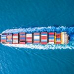 overhead shot as cargo ship sails on a blue sea.