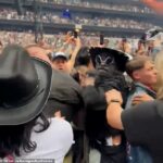 Um fã vestido com estofos pretos de cowboy preto lidou agressivamente outro membro da platéia