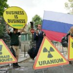 Os supostos ativistas do ambiente do Greenpeace têm cartazes, uma bandeira russa, caminhos de alerta oco e uma estátua de cera do presidente francês Emmanuel Macron