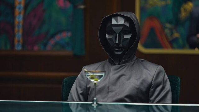 Homem sangrento e intenso em roupas formais fica abaixo da iluminação fria, seu smoking marcado com 