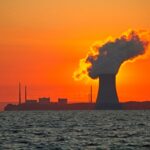 The sun rises behind a nuclear power plant cooling tower.