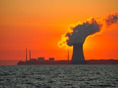 X-energy aproveita onda nuclear e levanta US$ 700 milhões Série D The sun rises behind a nuclear power plant cooling tower.