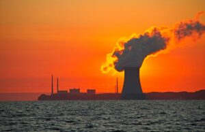 X-energy aproveita onda nuclear e levanta US$ 700 milhões Série D The sun rises behind a nuclear power plant cooling tower.