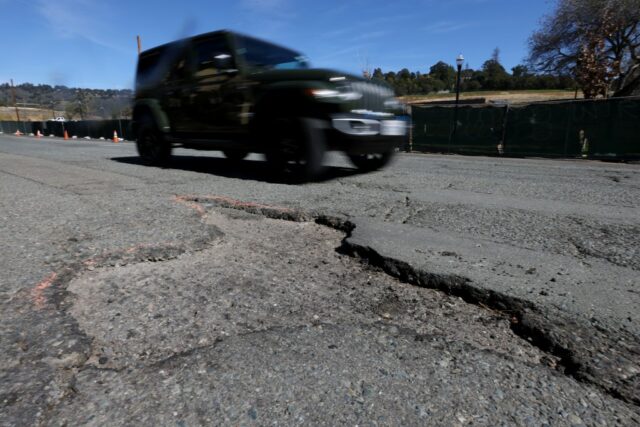 Na quinta -feira, 2 de março de 2023, um ciclista está entregando um grande buraco no Park Boulevard entre a Highway 13 e a St. James Drive em Oakland, Califórnia. 