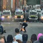 Vans policiais de Riot em Clonavon Terrace, Ballymena, quando as pessoas participam de um protesto por uma suposta agressão sexual na cidade de Co Antrim