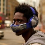 Duas pessoas que usam fones de ouvido Dysonzone, uma máscara de purificação de ar e uma sem