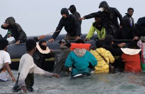 Caos em praias francesas como “comerciante humano humano” é visto migrantes de horror chicote enquanto eles rastejam para embarcar no barco para o Reino Unido Uma cerveja humana mascarada como uma marca uma bengala de açúcar e puxa uma jaqueta migrante enquanto eles tentam rastejar a bordo