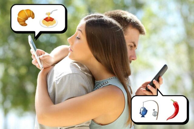 O homem fica sentado no sofá, olhando para o telefone enquanto a mulher está em segundo plano.