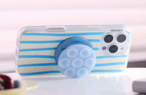 Mova -se, Octobuddy – Popsockets Primeira Sucção está aqui Uma pessoa que segura um telefone com um soquetes pop sugando garra preso a ele.