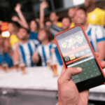 O legislador de Nova Jersey quer proibir rapidamente o micro jogo rápido. Pessoa que mantém um smartphone com uma apostas esportivas ao vivo -App Open, que mostra opções de apostas no futebol, enquanto um grupo incentiva os fãs empolgados em segundo plano em um bar.