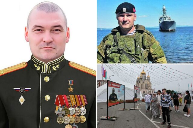 Divisão Geral Michail Gudkov de uniforme, com um navio de guerra em segundo plano.