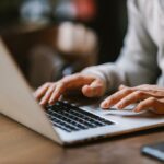 Fechar -Up of Writing Hands em um laptop em um café.
