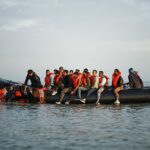 Os migrantes levam a bordo de um barco inflável de bote para atravessar o canal inglês, em cascalho