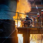 Steel workers releasing molten metal into a mould.