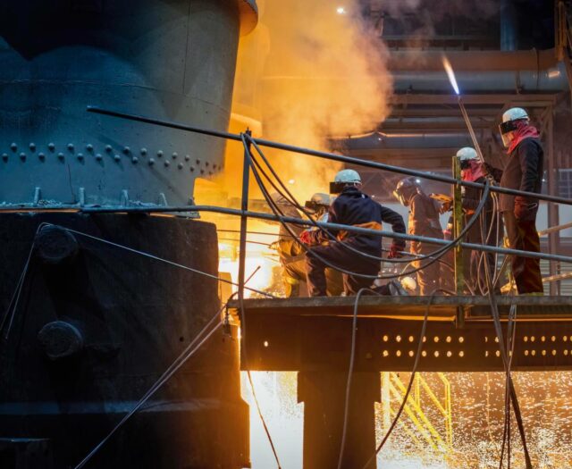 Steel workers releasing molten metal into a mould.