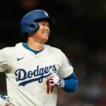Shohei Ohtani sorri no uniforme de Los Angeles Dodgers durante uma partida de beisebol.