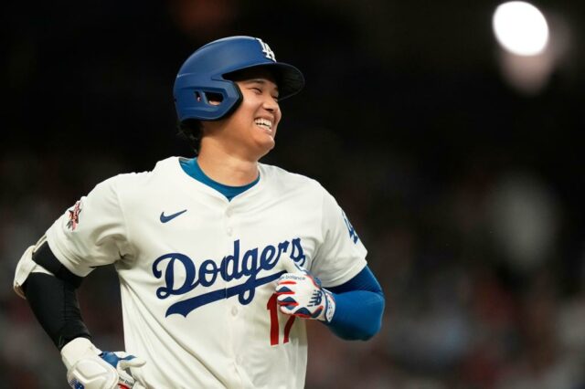 Shohei Ohtani sorri no uniforme de Los Angeles Dodgers durante uma partida de beisebol.