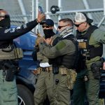 Immigration and Customs Enforcement (ICE) agents use their phones near protestors at a demonstration in Elizabeth, New Jersey May 7, 2025, outside Delaney Hall, a newly converted immigrant detention centre.