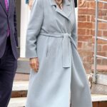 Queen Camilla (foto) parecia tipicamente elegante em um casaco azul pálido e chapéu creme de abas largas, completo com um arco