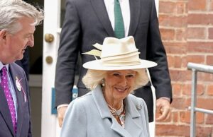 O Queen Camilla (foto) parecia tipicamente elegante em um casaco azul pálido e chapéu creme de abas largas, completo com um arco