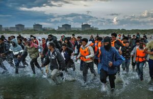 O Os migrantes correm pelo surf em Gravelines Beach, no norte da França, para embarcar em um bote de traficantes para a Grã -Bretanha no início deste mês