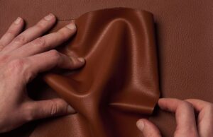 A Hyundai se uniu a uma start-up para desenvolver couro à base de plantas que cheira a couro de verdade Two hands crumple Uncaged Innovations' artificial leather.