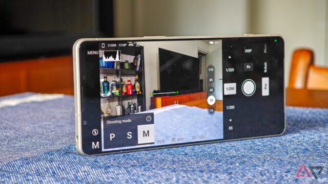 Uma foto do Sony Xperia 1 VI que descansa de lado em uma toalha de mesa azul, com o aplicativo da câmera e o botão lateral
