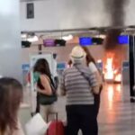 Os turistas atordoados olham para um incêndio iluminado no Terminal 1 do Aeroporto de Milão Malpensa