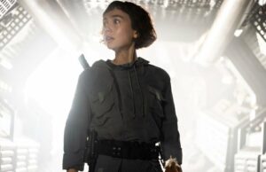 Alien: Terra: Qual é a diferença entre cyborgs, sintetizadores e híbridos? Um homem caminha pelo interior de uma nave espacial coberta com luzes amarelas brilhantes.