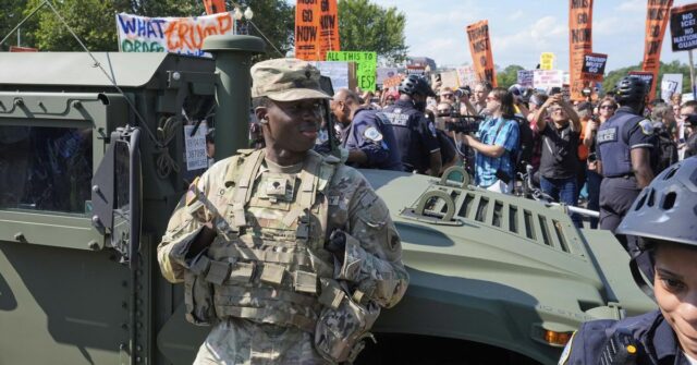 Os policiais de Washington Metropolita e os soldados da polícia militar da Região Columbia National Guardian Watch para ativistas protestam contra a aquisição federal do policiamento do policiamento do presidente do presidente Donald Trump.