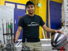 As empresas de foguetes canadenses estão correndo para lançar seus foguetes a partir de solo canadense, um mundo primeiro Quatorze homens ficam na frente de um foguete e alguns motores de foguete.