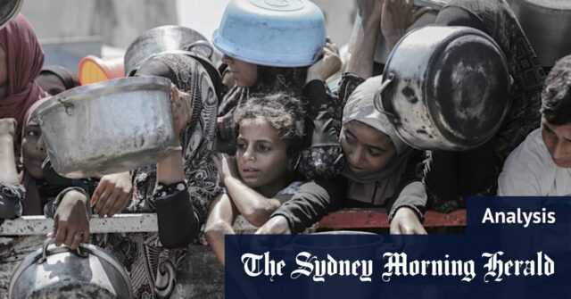 Os palestinos para esperar para coletar comida do amor da cozinha na cidade de Gaza.