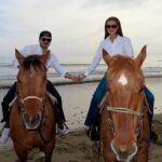 Brooklyn e Nicola seguram sua mão enquanto desfrutam de uma viagem a cavalo em uma bela praia