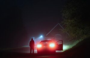 Erros de segurança no portal da web de um fabricante de carros permite que um hacker desbloqueie remotamente carros de todos os lugares A mysterious person standing next to a car on a spooky empty road on a foggy night. Silhouetted by street lights.