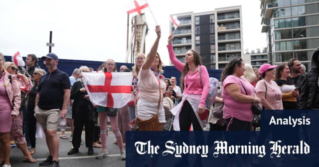 Duas mulheres detêm o padrão de St. George fora do hotel britânico para protestar Canary Wharf.
