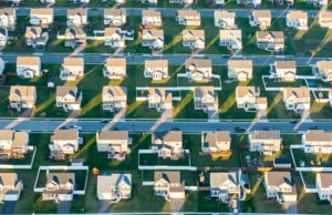 Esta startup de Detroit se transforma em programas de ajuda para tornar as atualizações da eficiência da casa mais baratas An oblique aerial view of suburban houses.