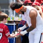 Denver Broncos Safety Talanoa Hufanga, à direita, assina um autógrafo para um jovem fã durante um campo de treinamento conjunto da NFL com o San Francisco 49ers, quinta -feira, 7 de agosto de 2025, em Santa Clara, Califórnia (AP Photo/Godofredo A. Vásquez)
