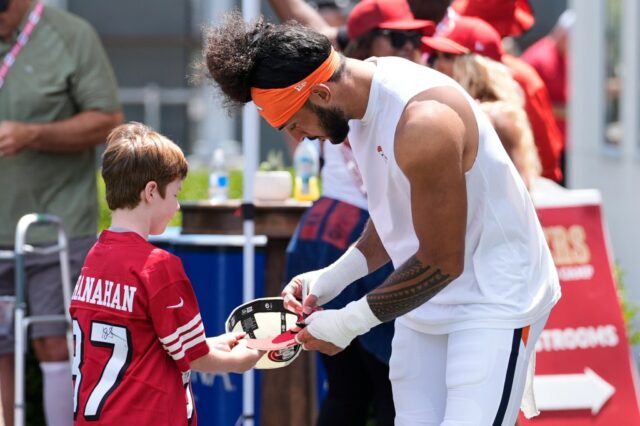 Denver Broncos Safety Talanoa Hufanga, à direita, assina um autógrafo para um jovem fã durante um campo de treinamento conjunto da NFL com o San Francisco 49ers, quinta -feira, 7 de agosto de 2025, em Santa Clara, Califórnia (AP Photo/Godofredo A. Vásquez)