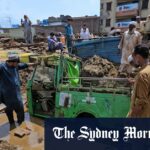 Moradores para remover a lama para recuperar o riquixá de detritos após inundações repentinas em Mingora, no noroeste do Paquistão.