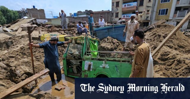 Moradores para remover a lama para recuperar o riquixá de detritos após inundações repentinas em Mingora, no noroeste do Paquistão.