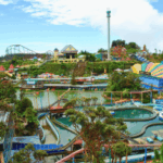 Parque de diversões coloridas do lado de fora em Genting Highlands, Malásia, com montanhas -russas, passeios de água, um lago centralmente com barcos de remo e prédios animados sob um céu azul claro. Genting Highlands Casino Chips Suspeito 'On the Run'